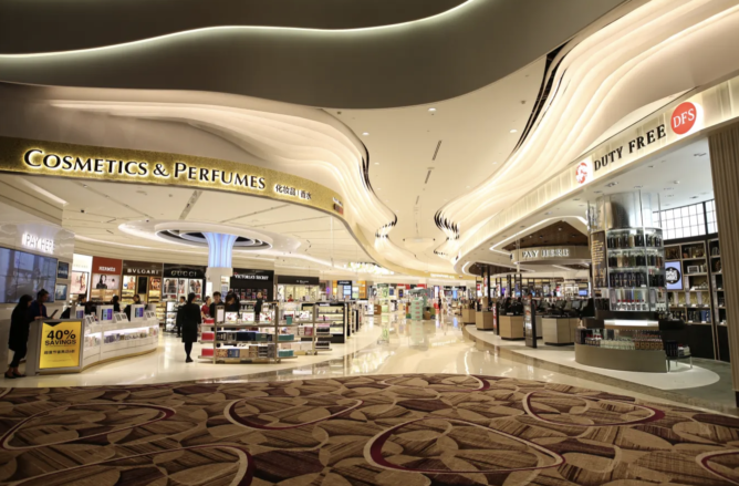 Pasażerowie przeglądają półki z alkoholami perfumami i kosmetykami w sklepie duty free