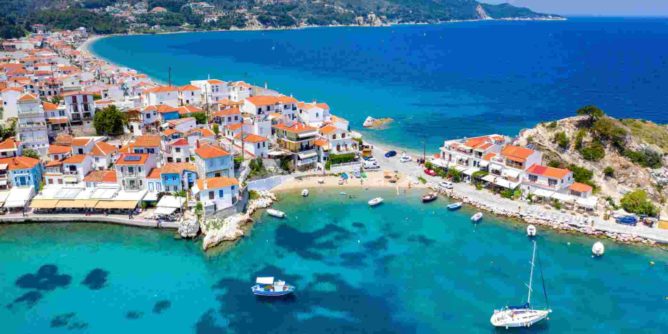 Słoneczna plaża w Grecji we wrześniu z turkusowym morzem i leżakami