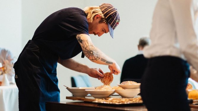 Kelner w eleganckiej restauracji zbiera napiwki z różnych walut świata