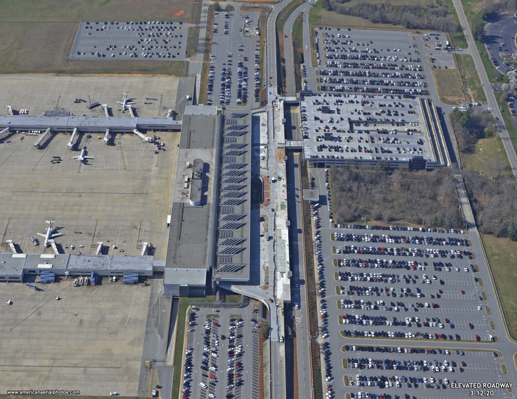 shuttle bus podjeżdżający do parkingu z pasażerami wysiadającymi z samochodów